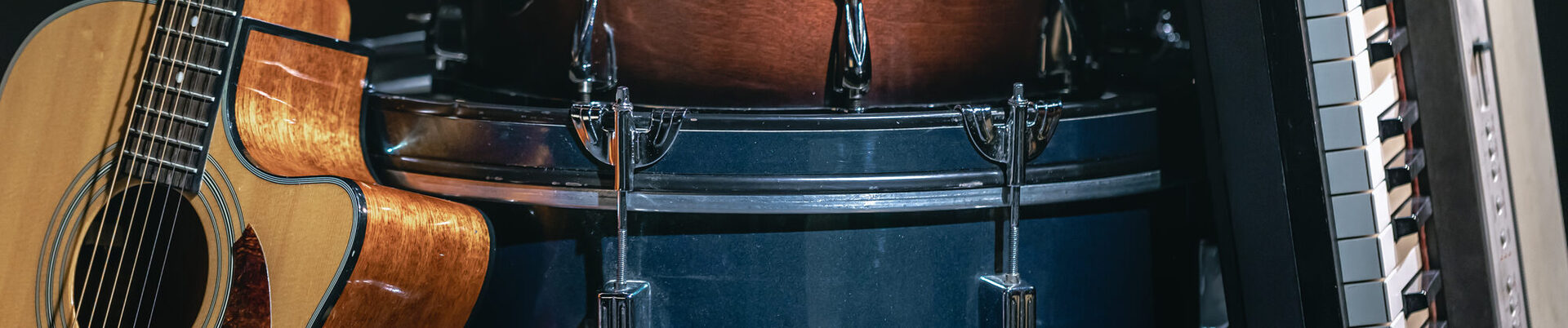 Acoustic guitar, drums and keys on a black background.