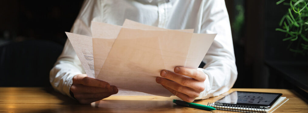 Cropped photo of young readhead bearded man working with papers