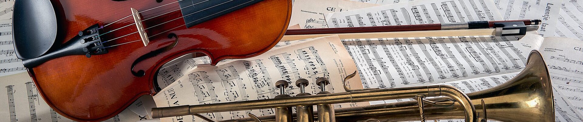 Closeup of a violin and a trumpet on note sheets under the lights - perfect for musical concepts