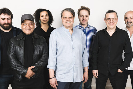 Group photo of six men and one woman in front of a white wall.
